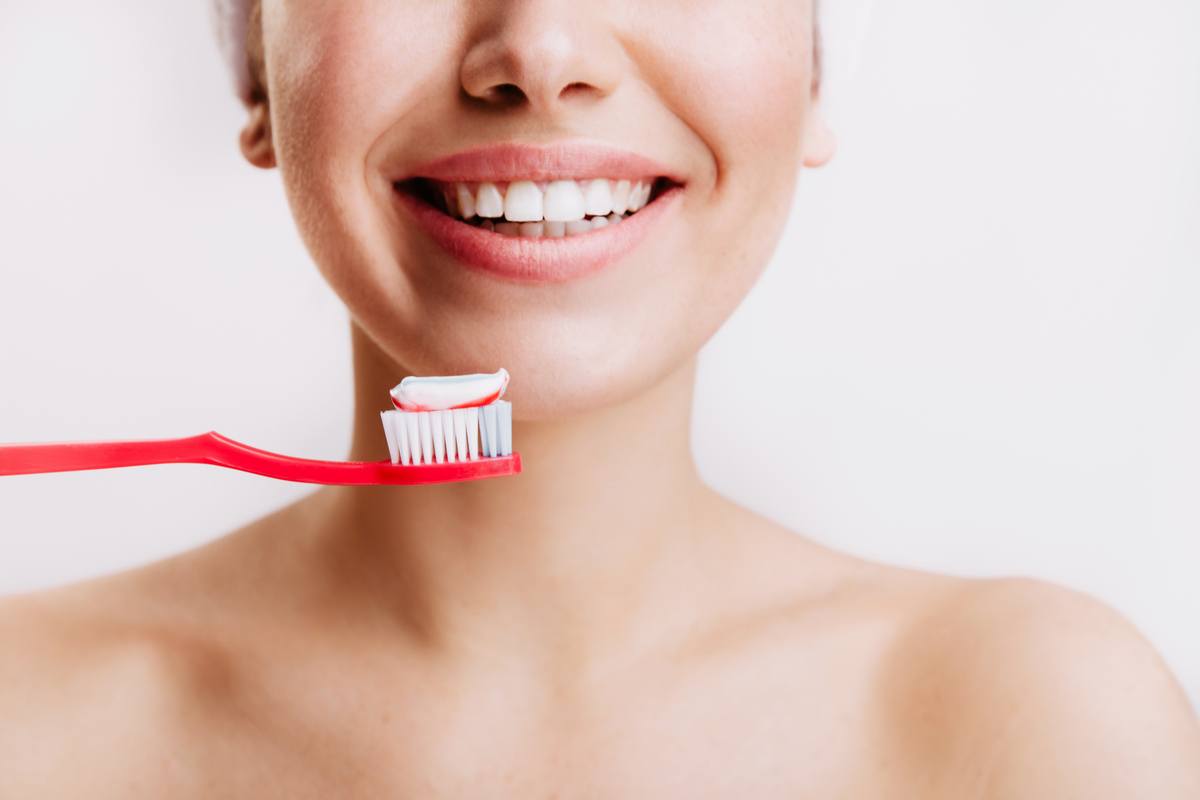 Girl with sincere smile makes morning routine and brushes her teeth on isolated background. Догляд за зубами