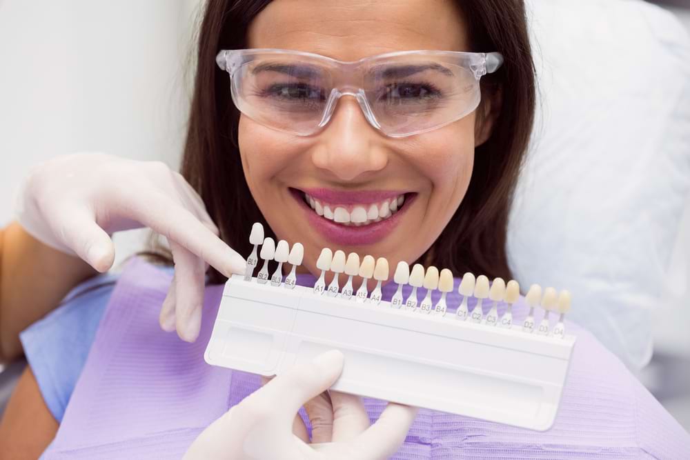 dentist-examining-female-patient-with-teeth-shades (1) Відбілювання зубів в Одесі